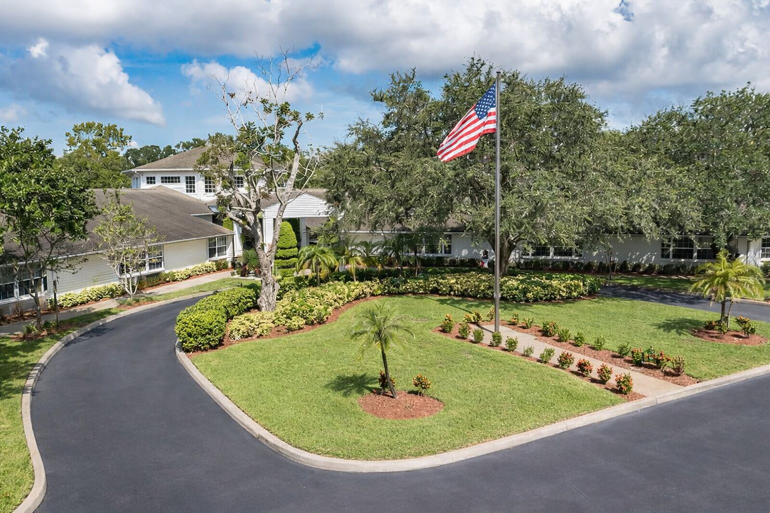Front of Colliers at Clearwater senior living community with American flag and landscaped grounds