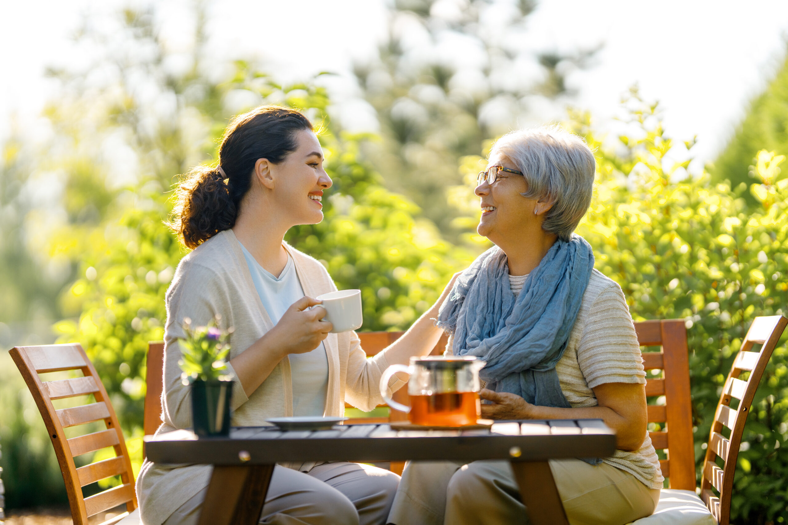 A daughter and her elderly mother in a warm, quiet conversation at a kitchen table